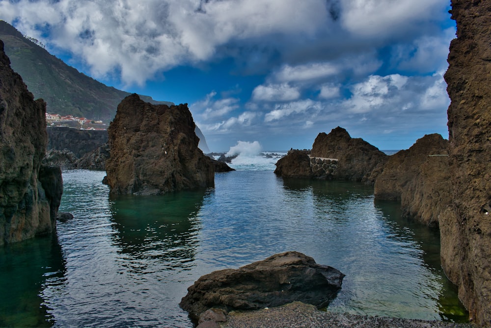 brown rocky mountain beside body of water under blue and white sunny cloudy sky