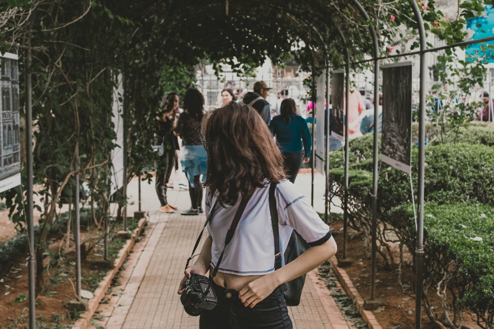 woman in white shirt and black pants carrying black leather shoulder bag walking on train rail