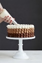 person holding white ice cream cone with brown and white round cake