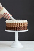 person holding white ice cream cone with brown and white round cake
