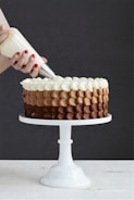 person holding white ice cream cone with brown and white round cake