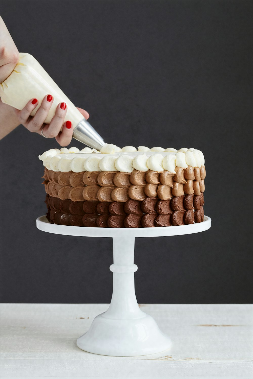 person holding white ice cream cone with brown and white round cake