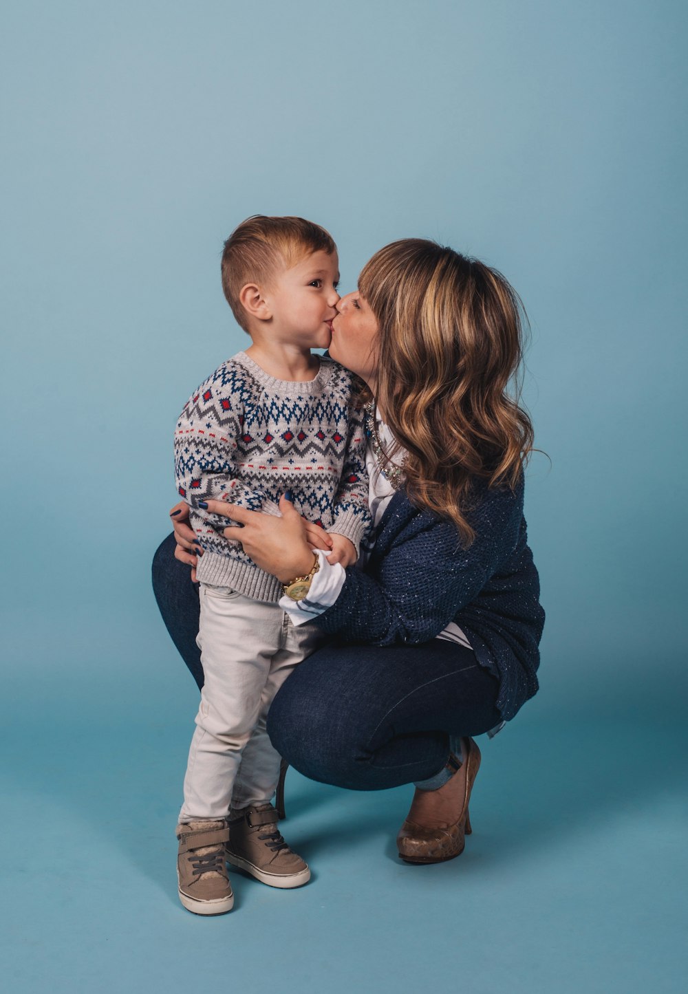 woman in black cardigan carrying baby in blue and white long sleeve shirt