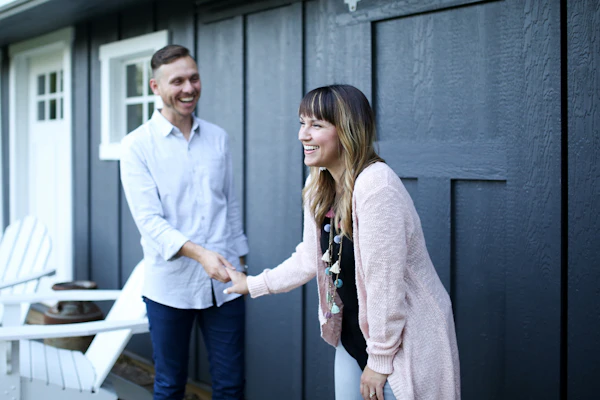 A homeowner shaking hands with a buyer on their front porch after agreeing to a direct sale