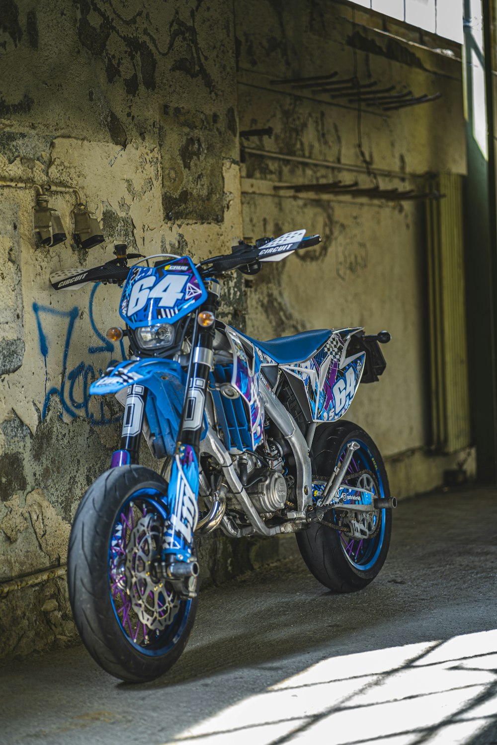 blue and black motorcycle parked beside wall
