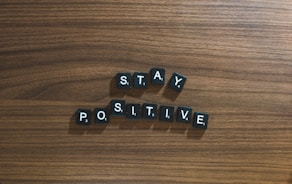 the word stay positive spelled in scrabble type on a wooden surface