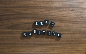 the word stay positive spelled in scrabble type on a wooden surface