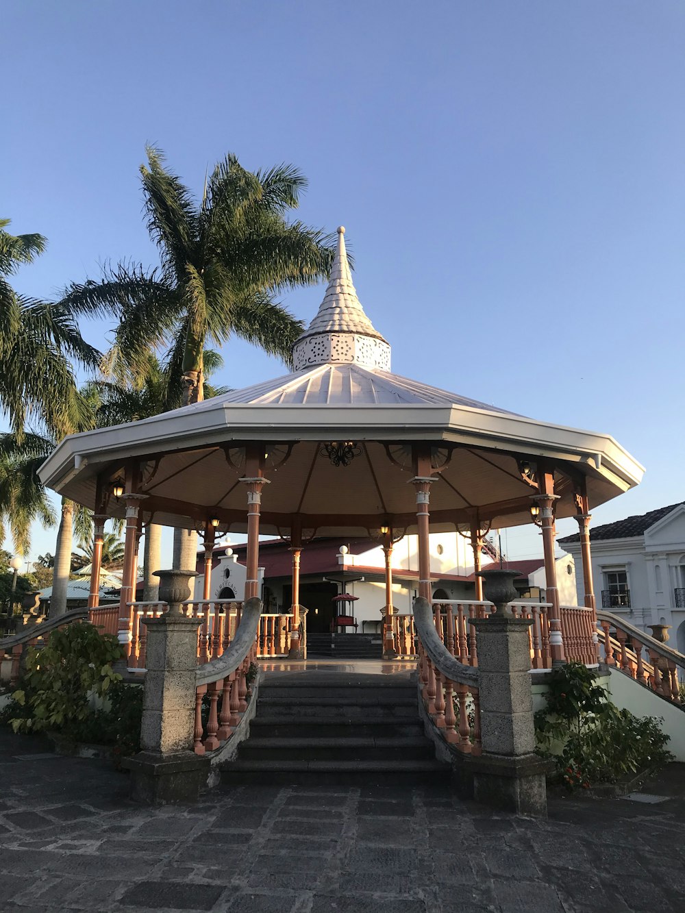 brown and white wooden gazebo surrounded by green trees during daytime