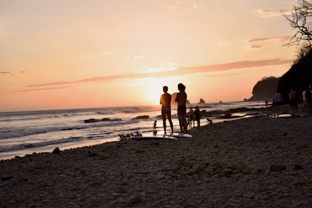 A serene beach scene with a small group enjoying a sunset yoga session near the ocean.