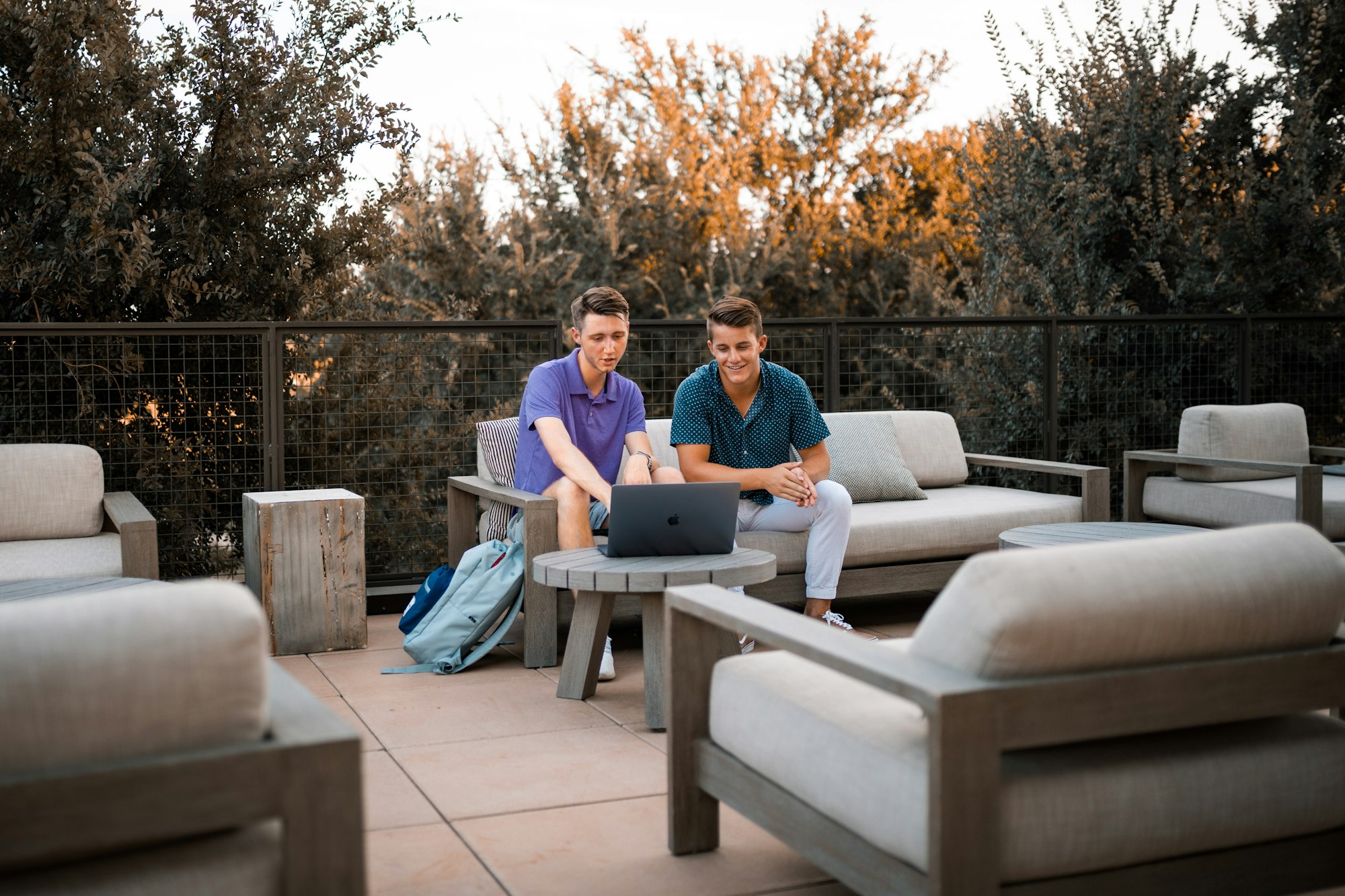 Two males working together on a computer outside.