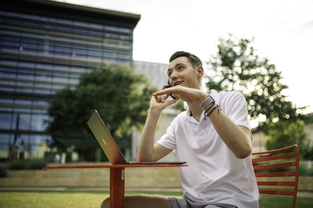 man in white crew neck t-shirt holding gray laptop computer