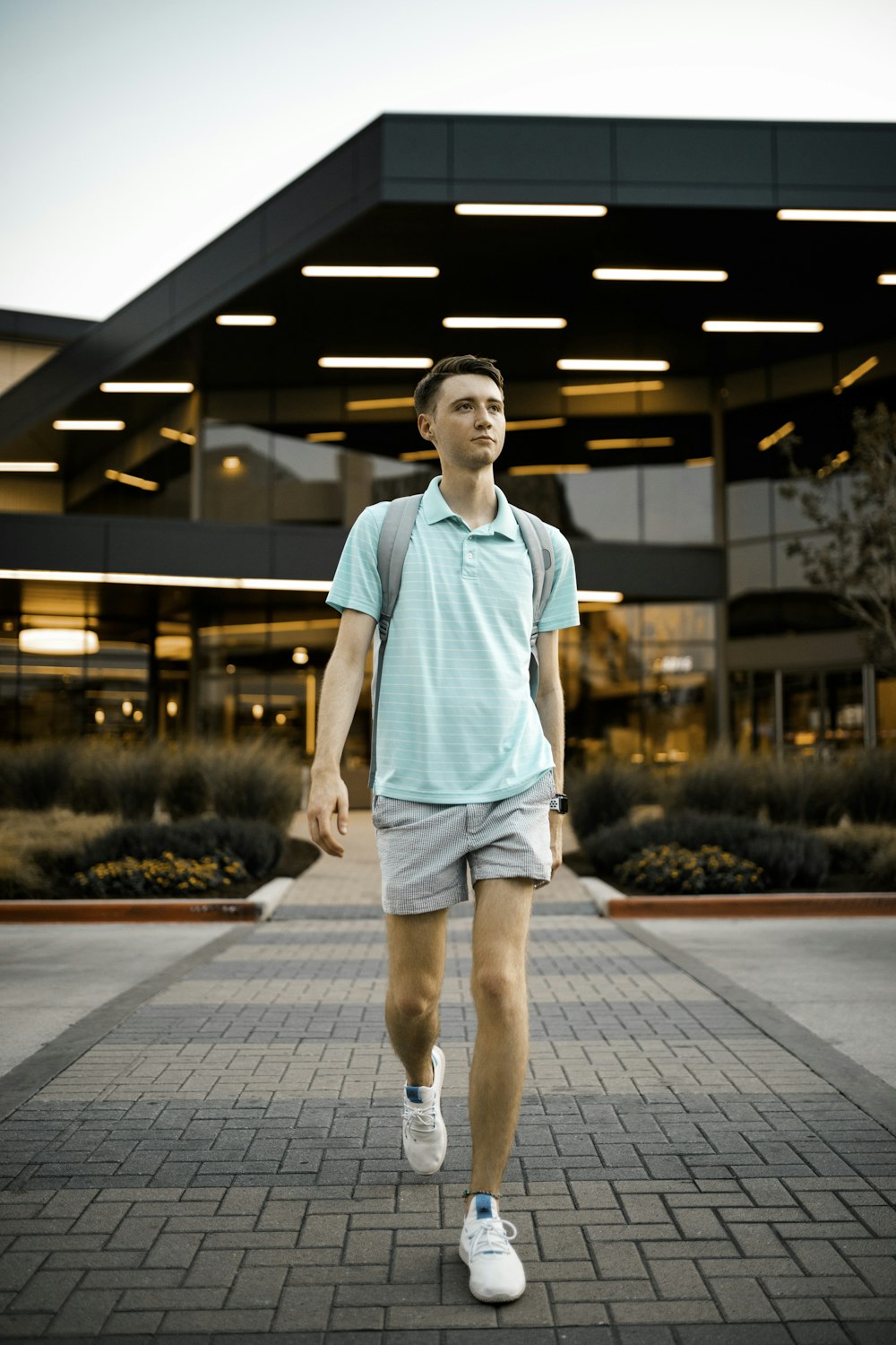 man in green crew neck t-shirt and blue denim shorts standing on gray concrete pavement