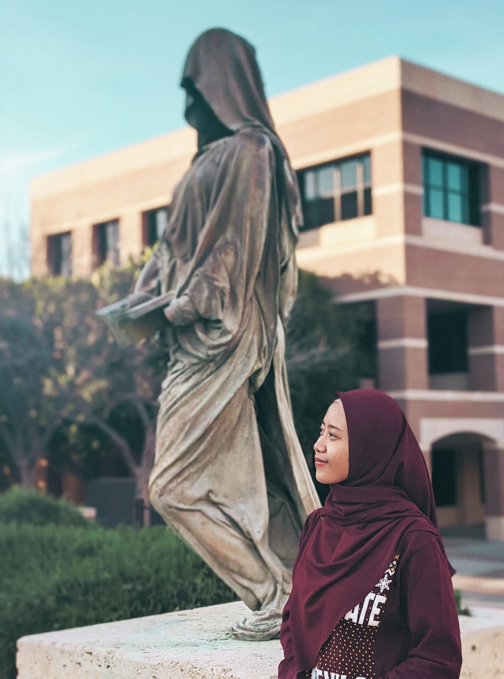 像のそばに立つ赤いヒジャーブの女性