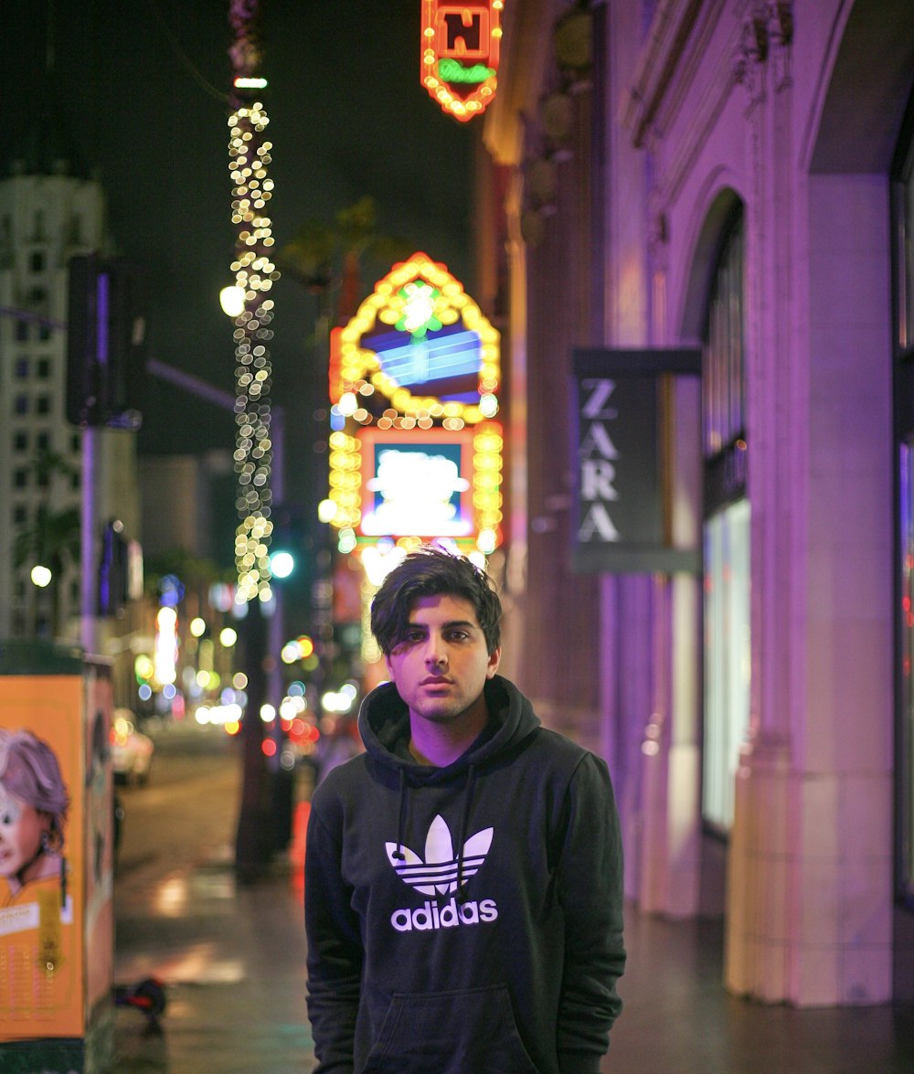 man in black hoodie standing near building during nighttime