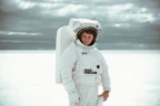Model wearing white 'Astronaut Alone' jacket against dark backdrop emphasizing minimalist design