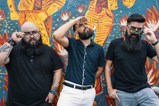 A group of diverse men confidently posing in casual streetwear tees against a graffiti wall.