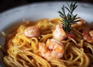 pasta with cream and green leaf on white ceramic bowl