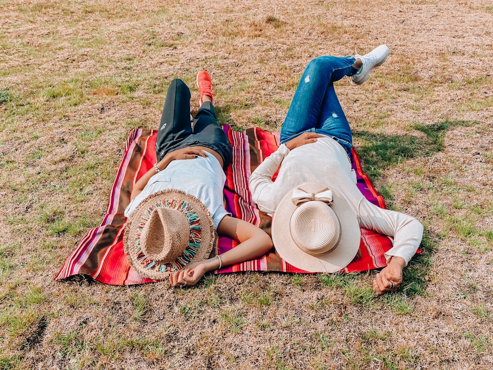 woman in brown sun hat lying on green grass field during daytime