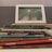 A stack of poetry books sits on a surface, with titles like 'Missing You, Metropolis' and 'Revolutionary Petunias & Other Poems.' On top of the stack is a framed photograph depicting a hand reaching up and holding a star against a cloudy sky.