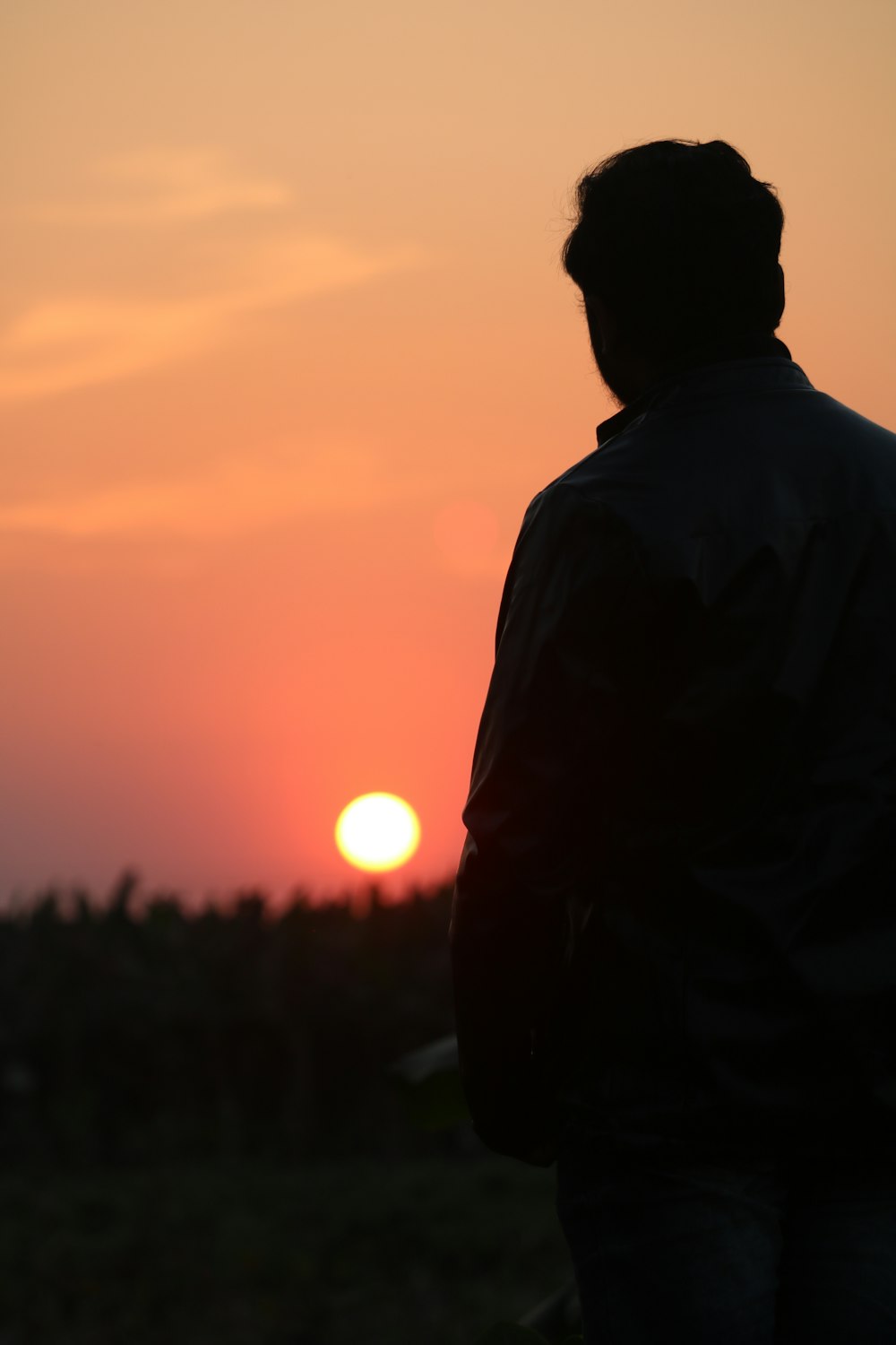 man in black jacket standing during sunset