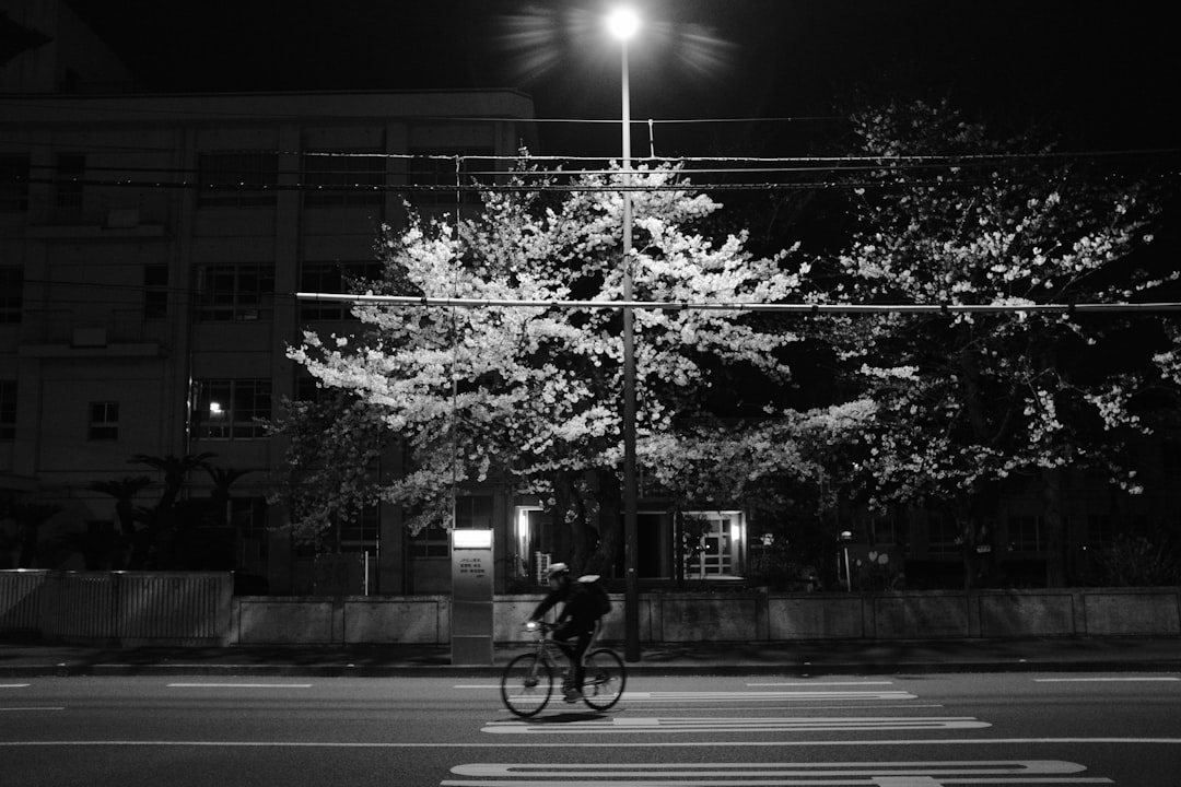 grayscale photo of man riding bicycle on road