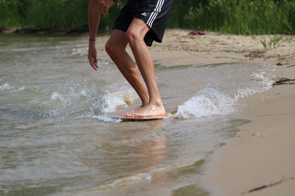 person in black shorts running on water during daytime