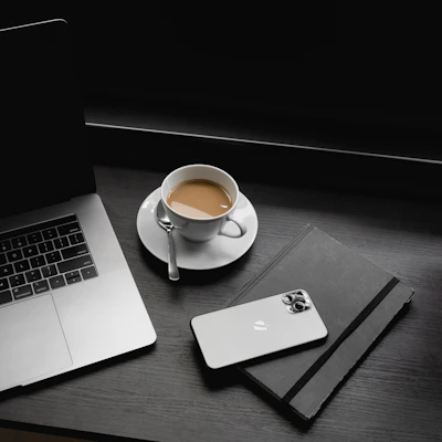 macbook pro beside white ceramic teacup on saucer