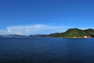 body of water near mountain under blue sky during daytime