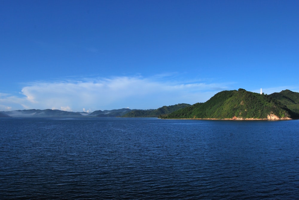 body of water near mountain under blue sky during daytime