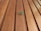 A green insect, possibly a katydid, is perched on wooden planks that exhibit a natural grain and warm tones.