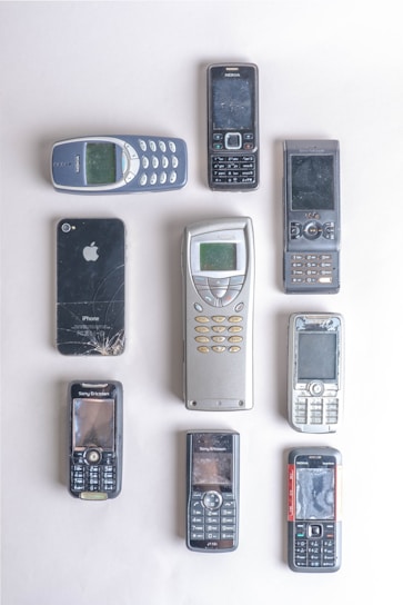 A collection of well-kept secondhand phones laid out on a colorful cork surface.