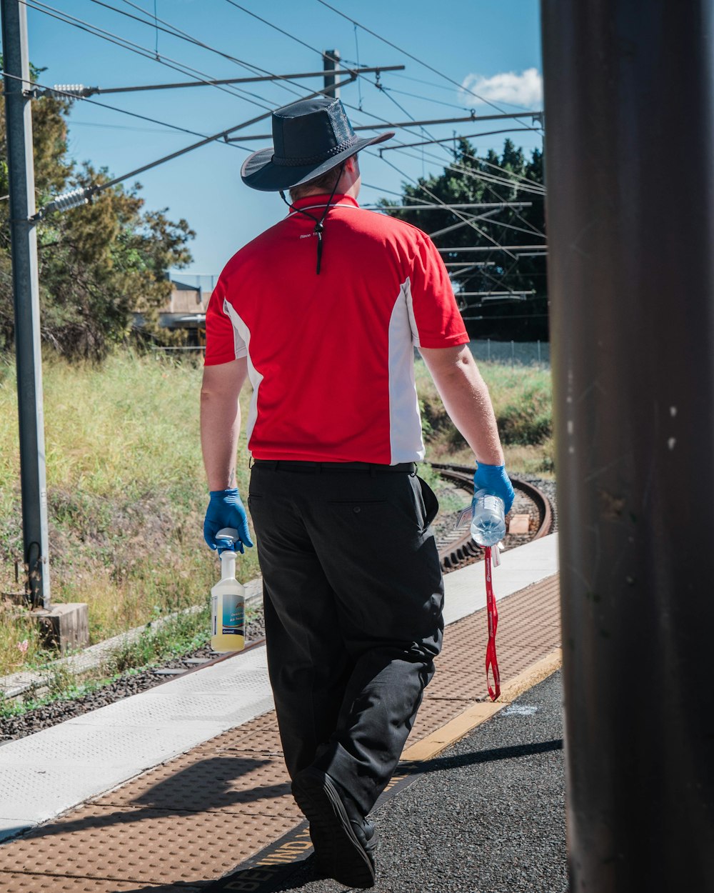 Hombre con polo rojo y pantalones negros sosteniendo una botella de agua de plástico azul