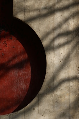Abstract shadows cast on cracked concrete wall, layered with dark red tone accents.
