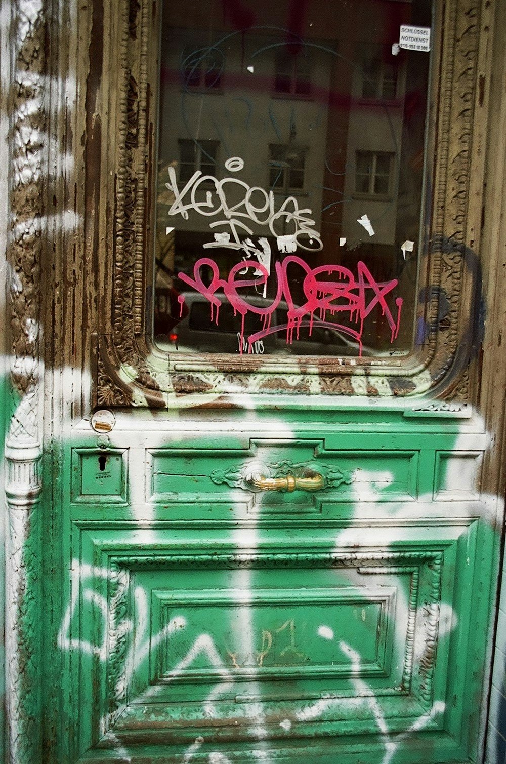 une commode verte avec des graffitis dessus devant une fenêtre