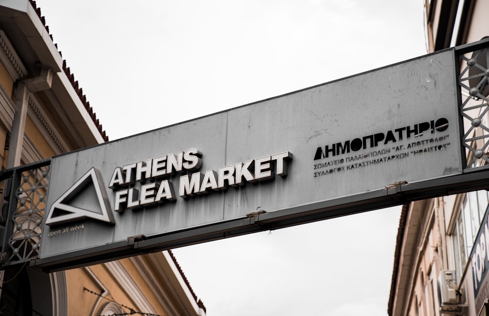 a sign for a flea market hanging off the side of a building