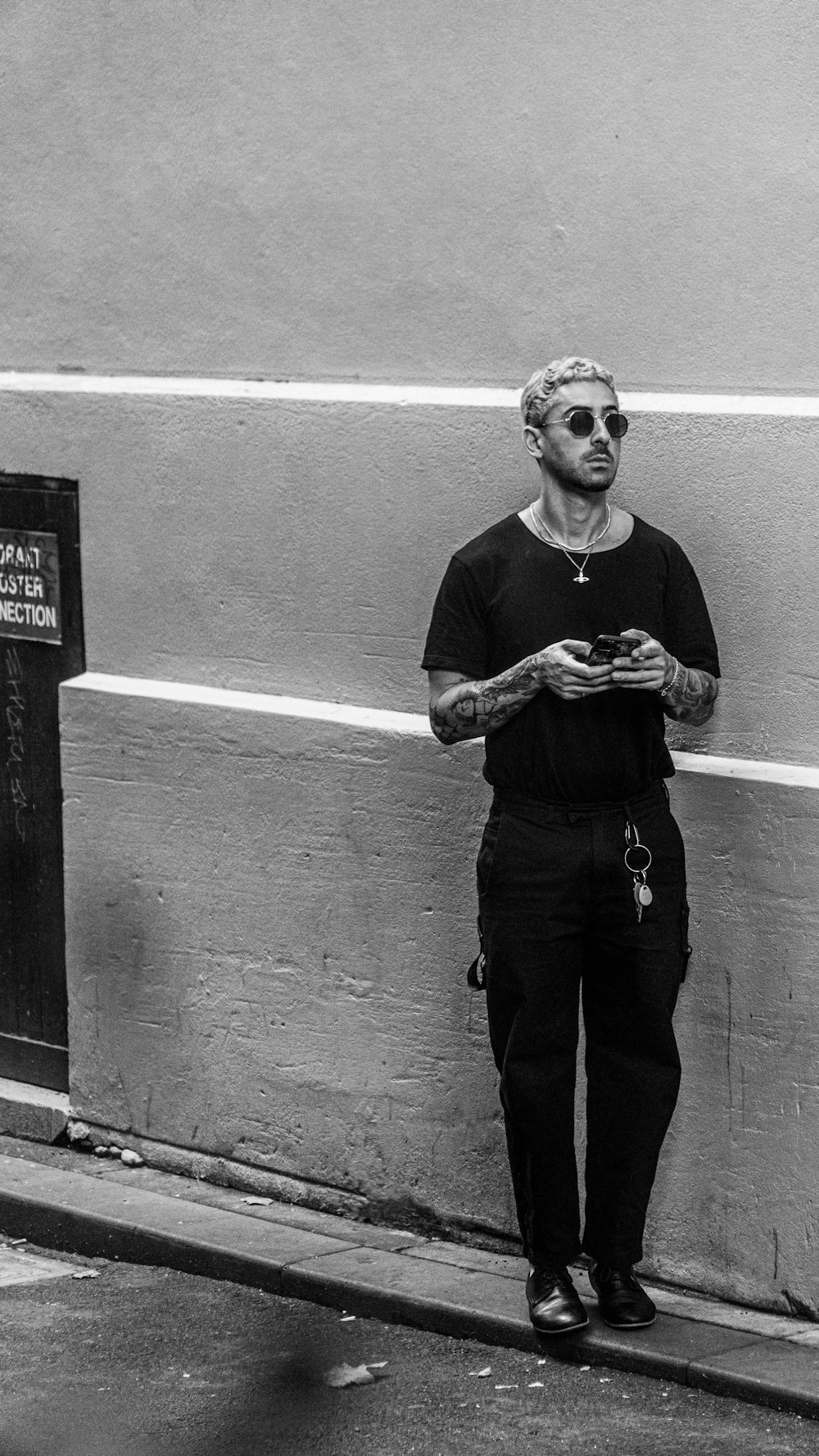 man in black crew neck t-shirt and black pants standing beside wall