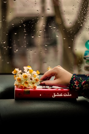 Close-up of a hand picking a well-loved novel from Bloom Wild's curated collection.