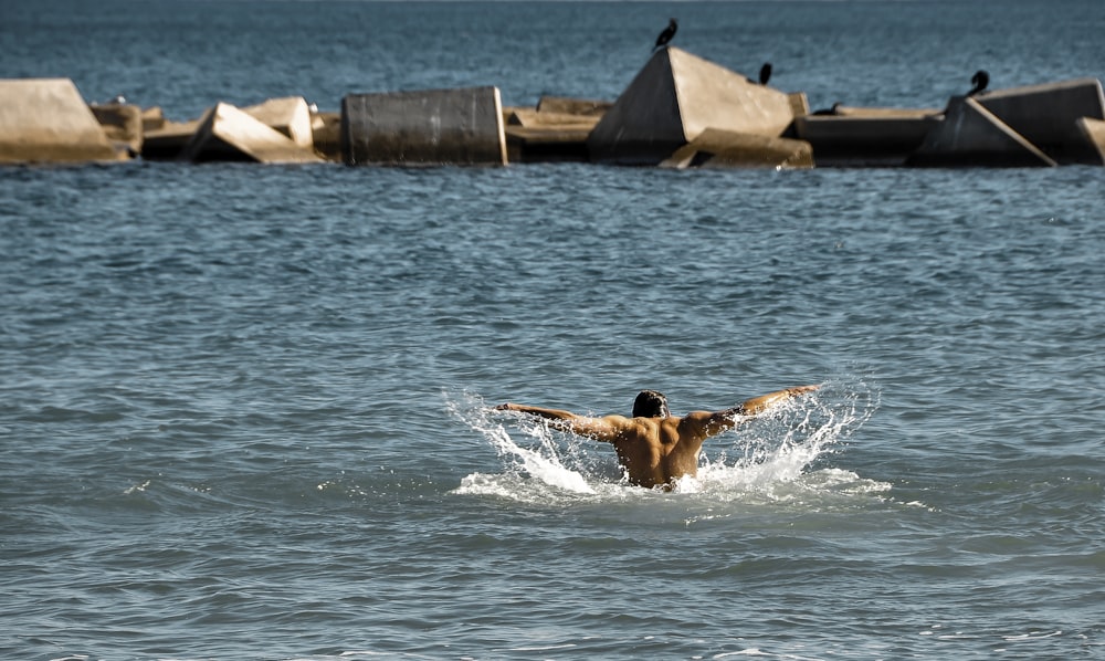 hombre en pantalones cortos azules nadando en el agua durante el día