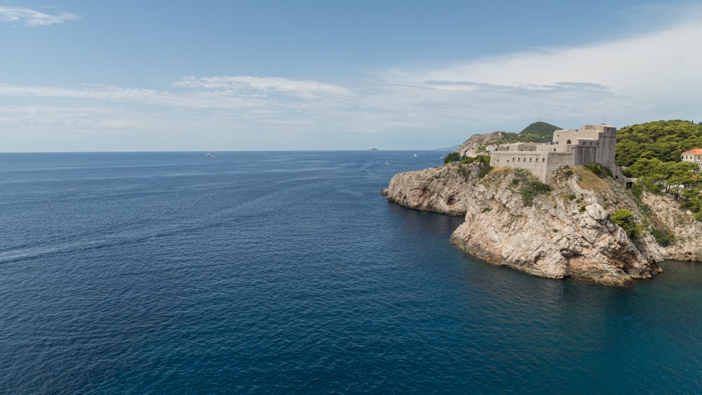 white and brown concrete building on cliff by the sea under blue sky during daytime