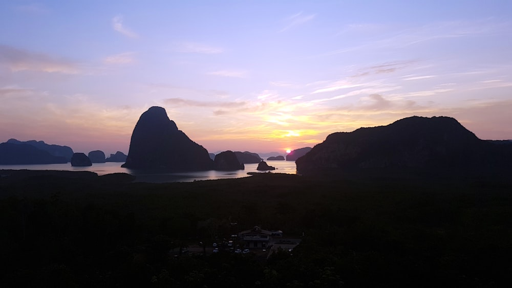 silhouette of mountain near body of water during sunset