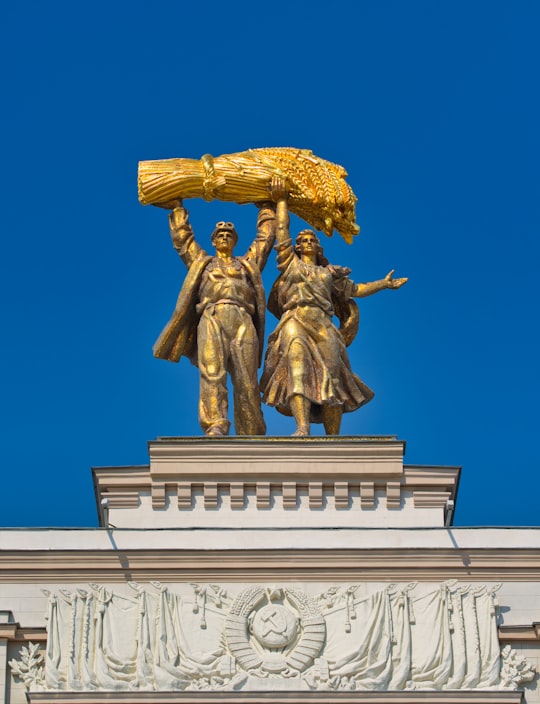 gold statue of man holding gold crown in アルカ・グラヴノヴォ・フホダ VDNKh Russia