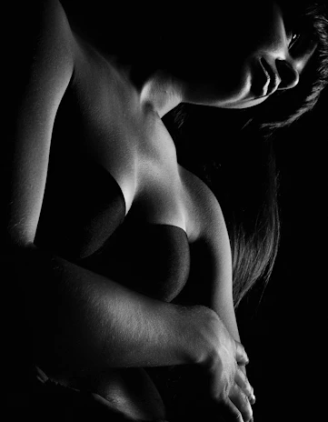A striking black-and-white boudoir portrait capturing intimate elegance and soft shadows.