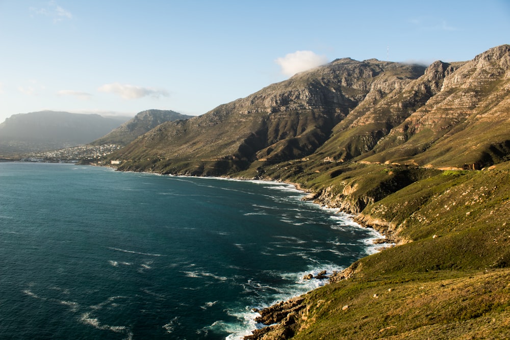 green and brown mountains beside blue sea under blue sky during daytime