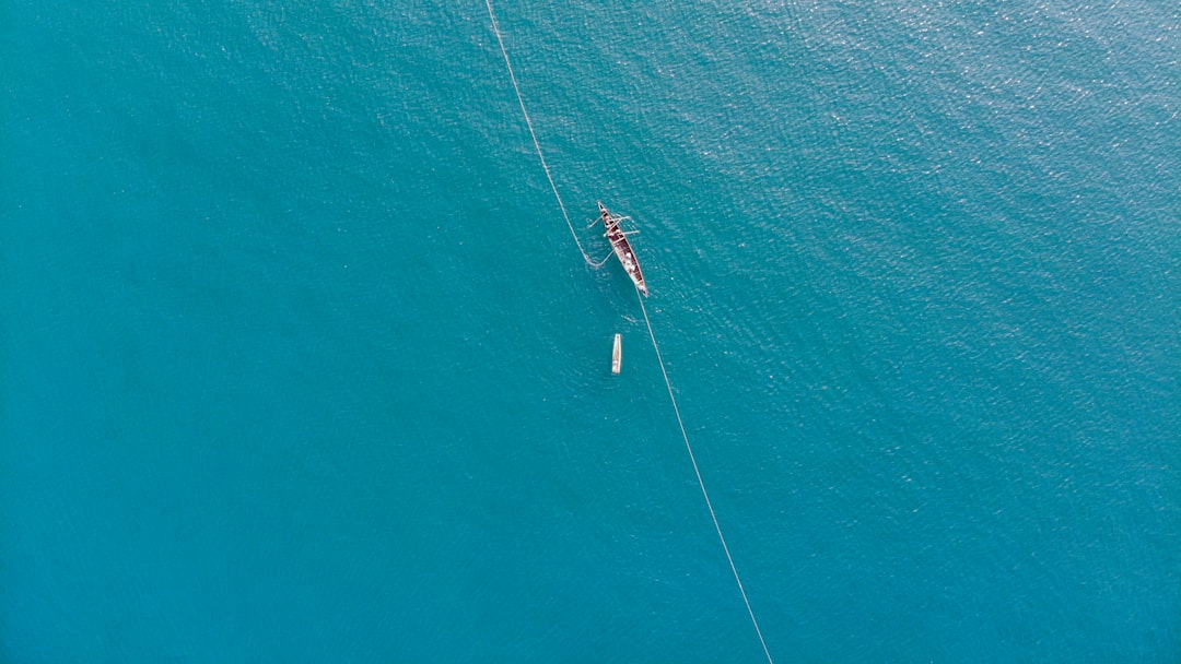 2 person in white and red boat on blue sea during daytime