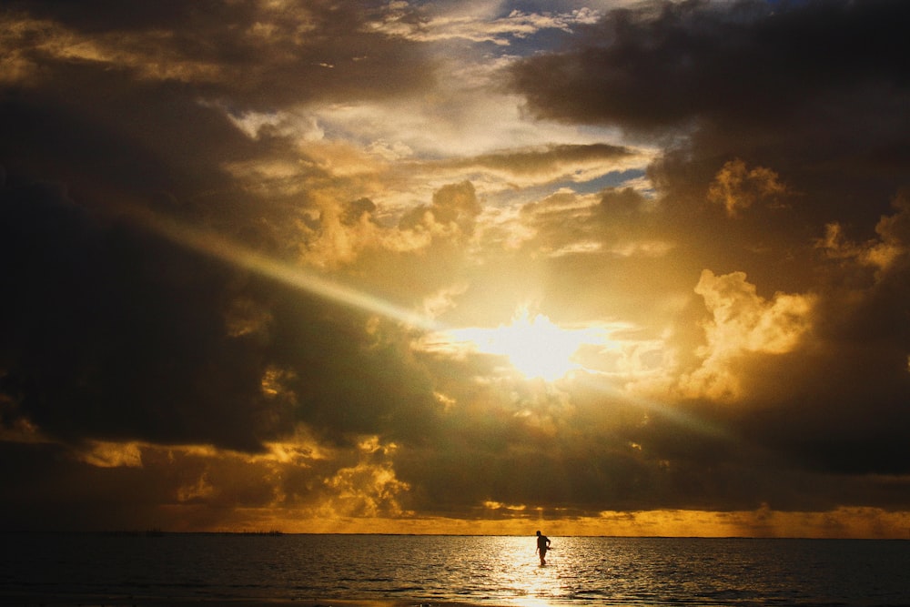 silhouette of 2 people on sea during sunset