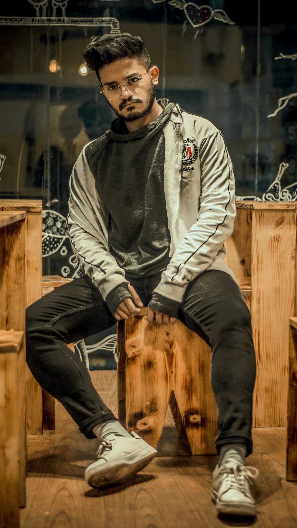 man in gray and black hoodie and black pants sitting on brown wooden seat