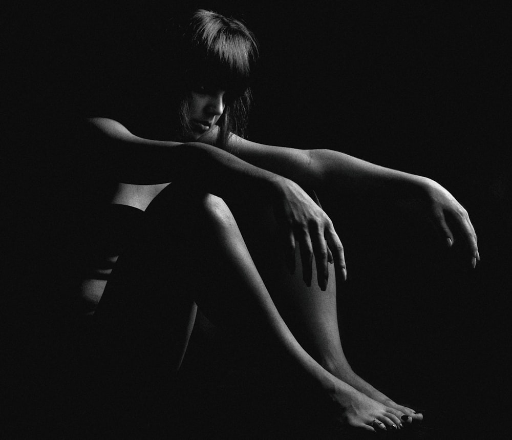 topless woman sitting on black surface