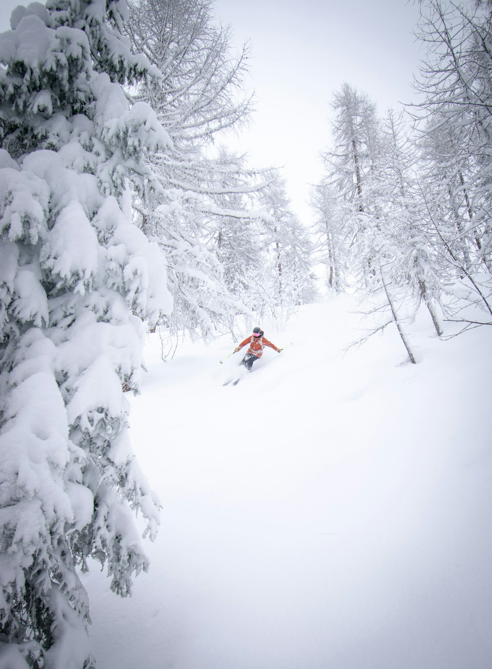 person in red jacket and black pants on snow covered ground during daytime