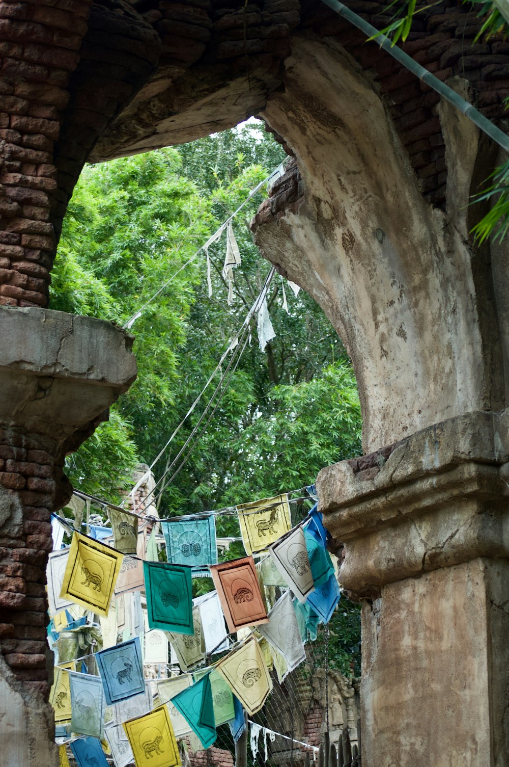 blue yellow and green textiles hanging on brown concrete post during daytime