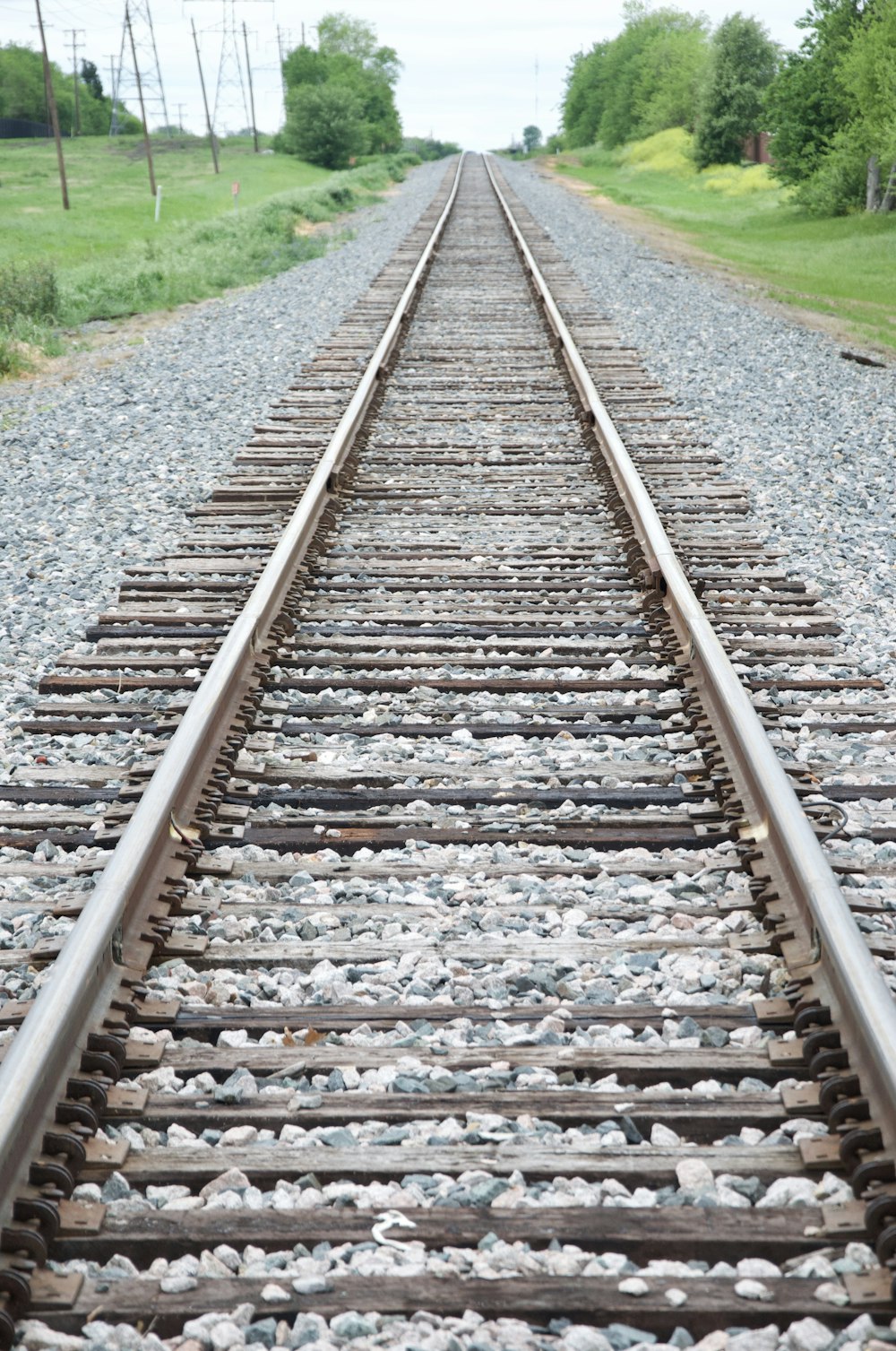 brown train rail near green grass field during daytime